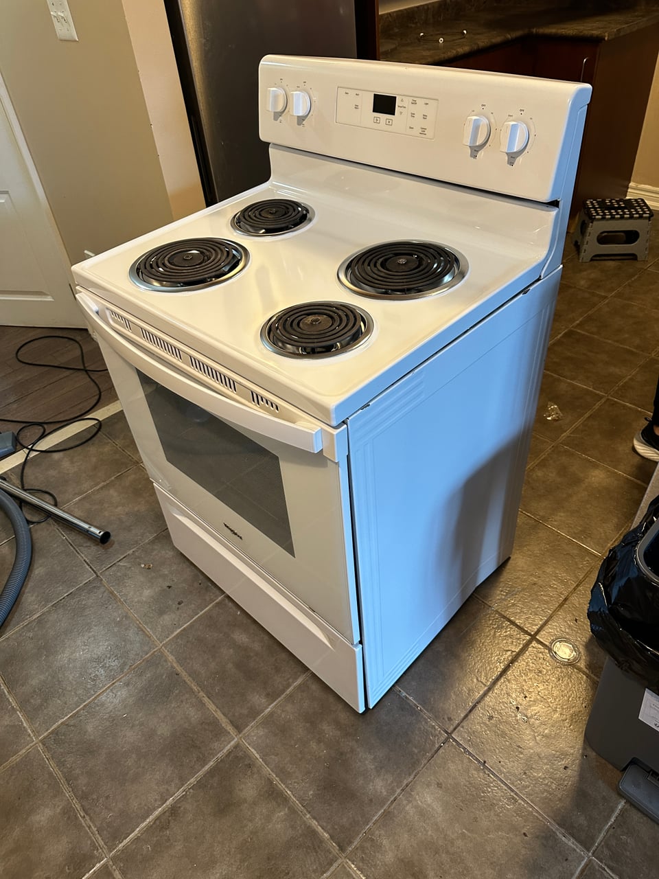 White electric stove after cleaning, with a clear cooktop, fitted coil burners and a clean side panel.
